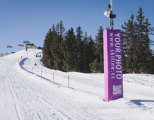 Ein Kind fährt über eine Wellenbahn in der Funslope und balanciert geschickt auf den Skiern. Die Strecke ist durch bunte Markierungen und Sicherheitszäune gekennzeichnet. | © Stefanie Oberhauser